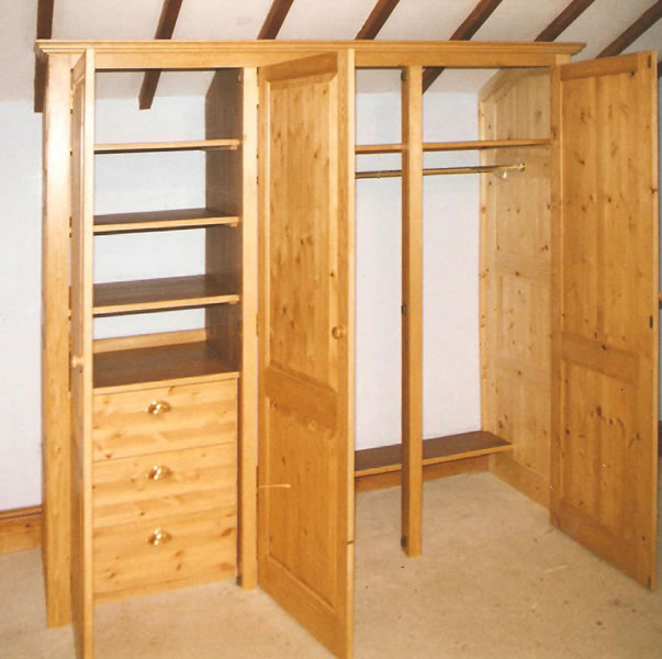 Pine wardrobe with raised and fielded panels showing internal hanging space shelf storage and drawers