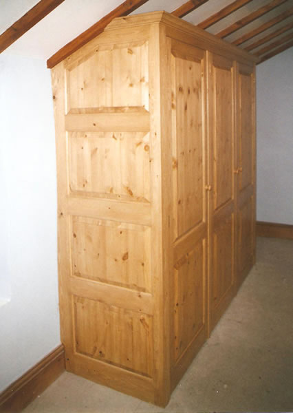 Pine wardrobe with raised and fielded panels side veiw showing scribed fit to the sloped ceiling