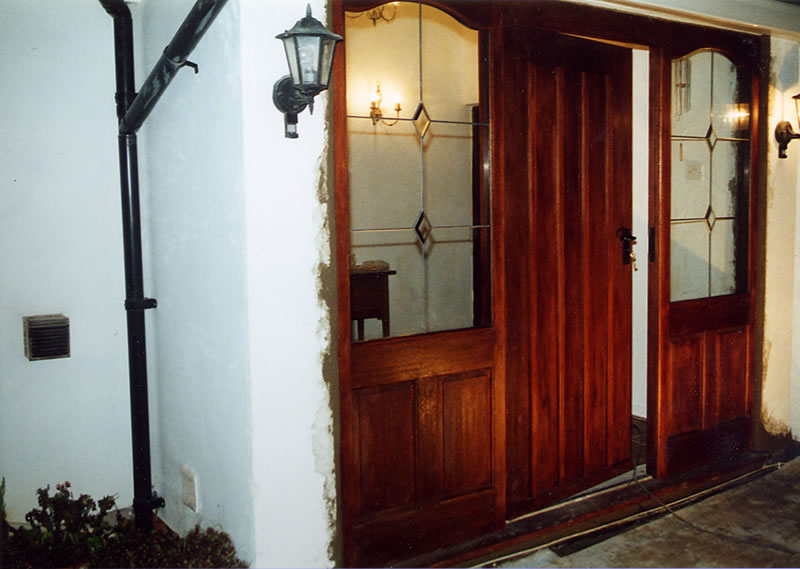 Door and frame designed to match early style plank doors with a baton nailed-over-joints-curved-tops-of-the-panelled-side-lights-to-soften-the-otherwise-square-appearance