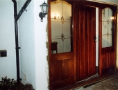 Door and frame designed to match early style plank doors with a baton nailed-over-joints-curved-tops-of-the-panelled-side-lights-to-soften-the-otherwise-square-appearance